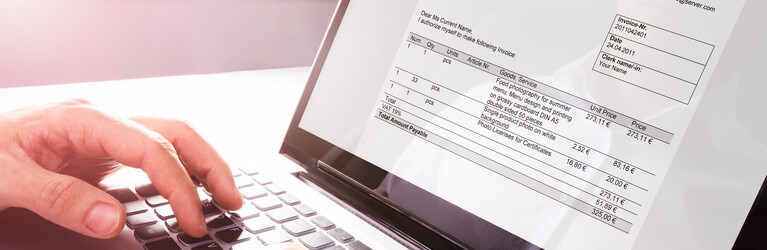 Businessman's Hands Working On Invoice On Laptop