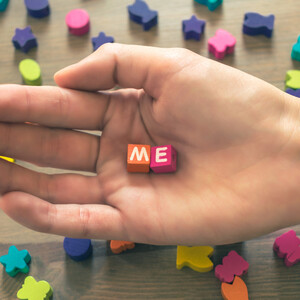 The pure thoughtful hand of a beautiful young girl holds colored cubes with the inscription Me - close-up